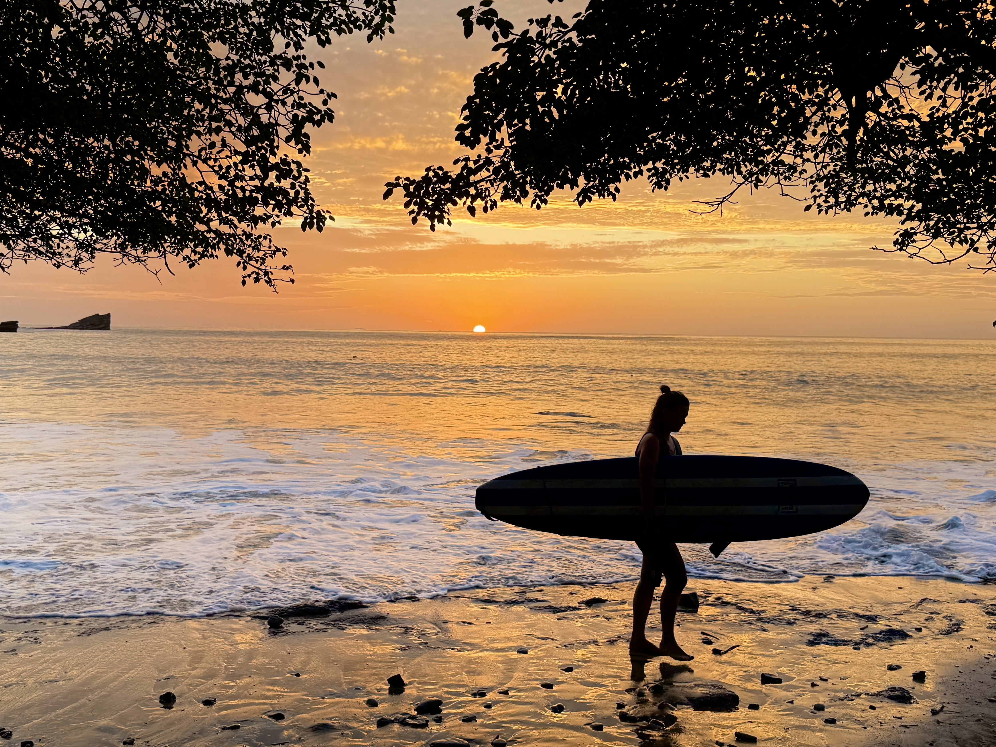 Surfer at sunset in Playa Guiones, Nosara